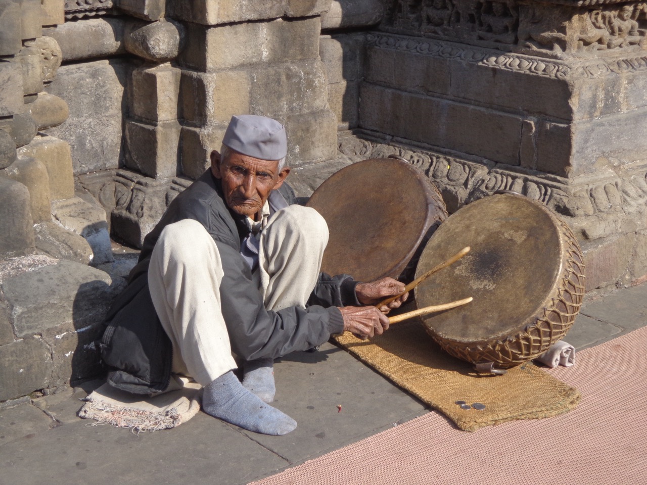 A drummer drums and begs inside the temple.