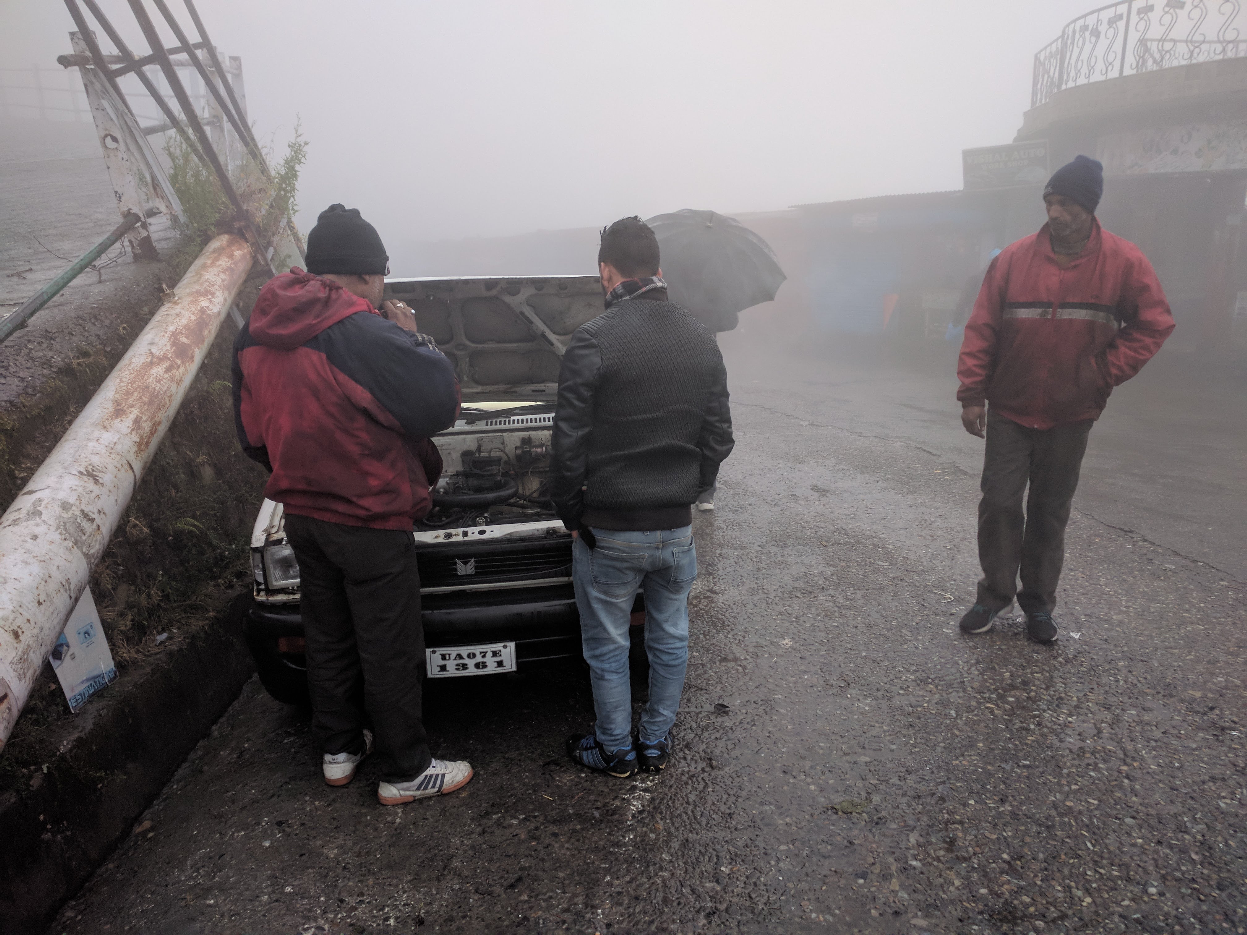 A couple of guys trying to jump-start a cold and rain-soaked car.