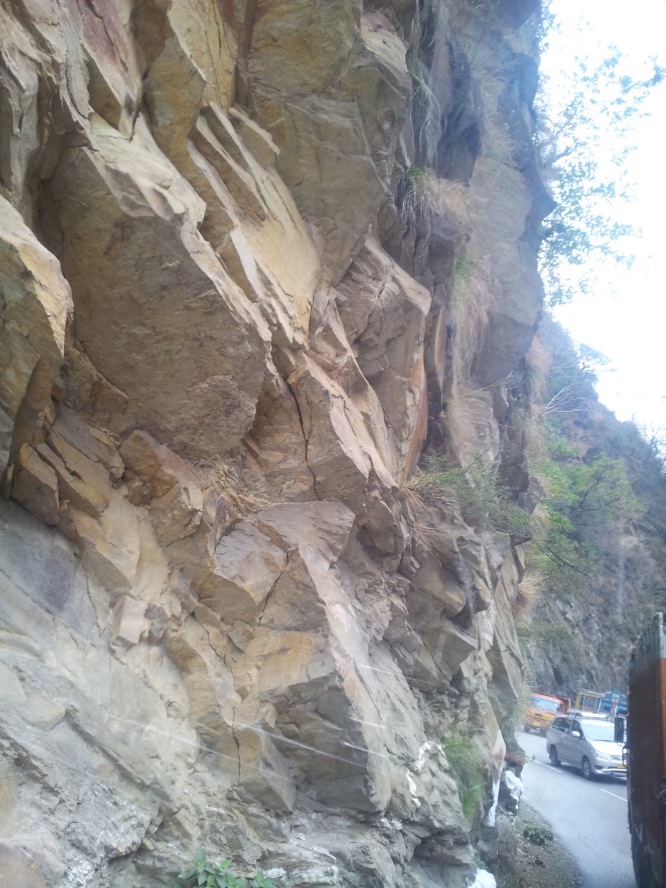 The rock wall on one side of the highway is absolutely vertical.