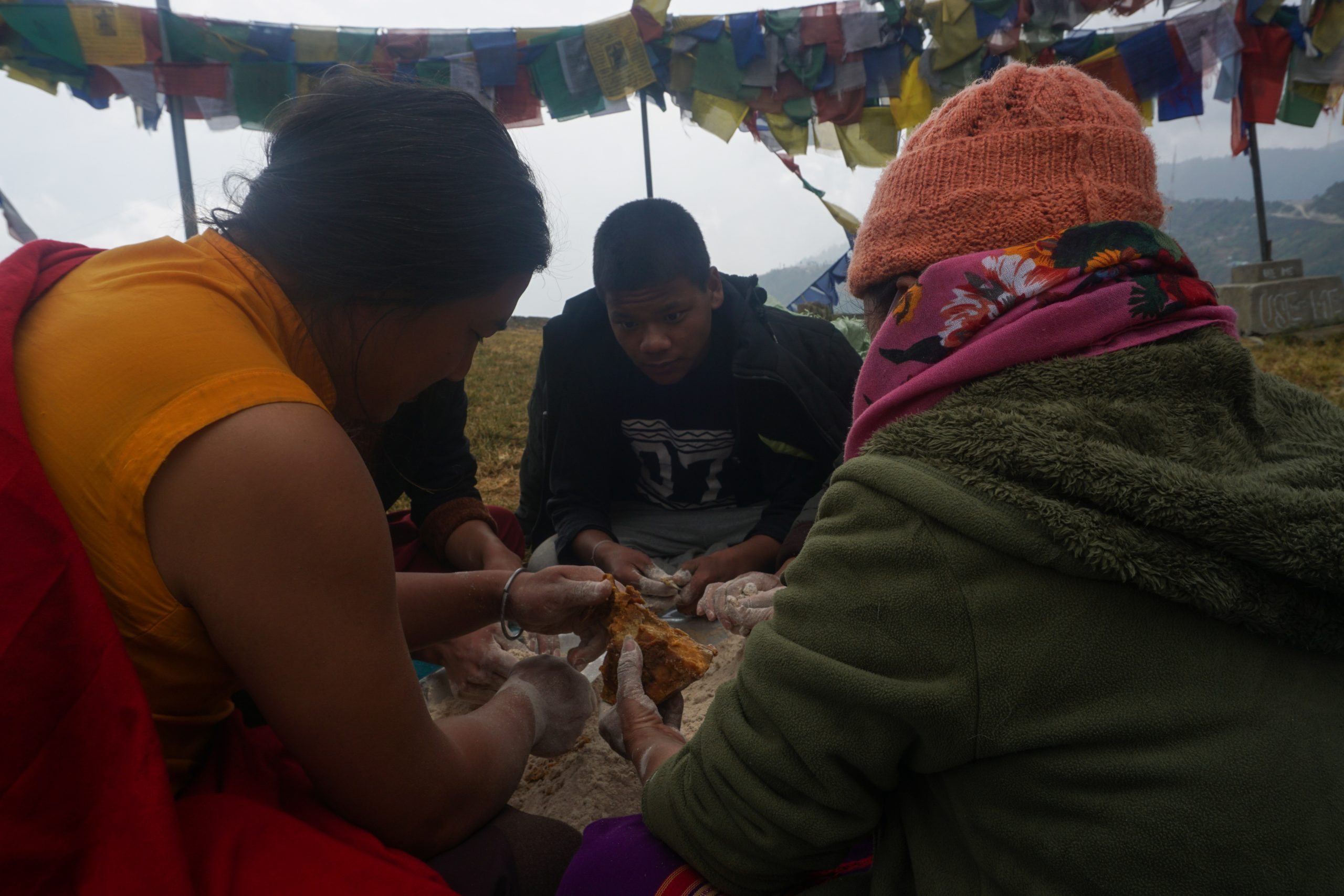 Monks and their family members preparing an offering of jaggery, wheat flour, and butter.