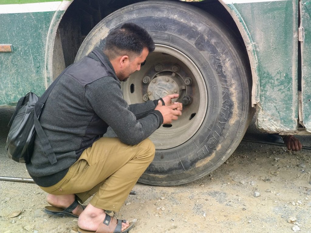The conductor unscrewed the tyre while the driver engaged a jack. (You can see his hand.)