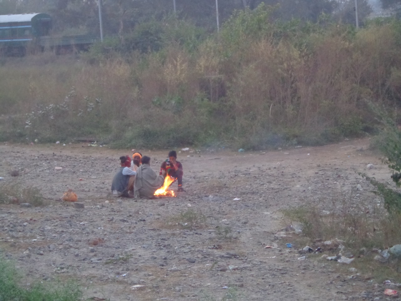 Guys warming themselves up near a bonfire just off the tracks at Pathankot Cantt. station.