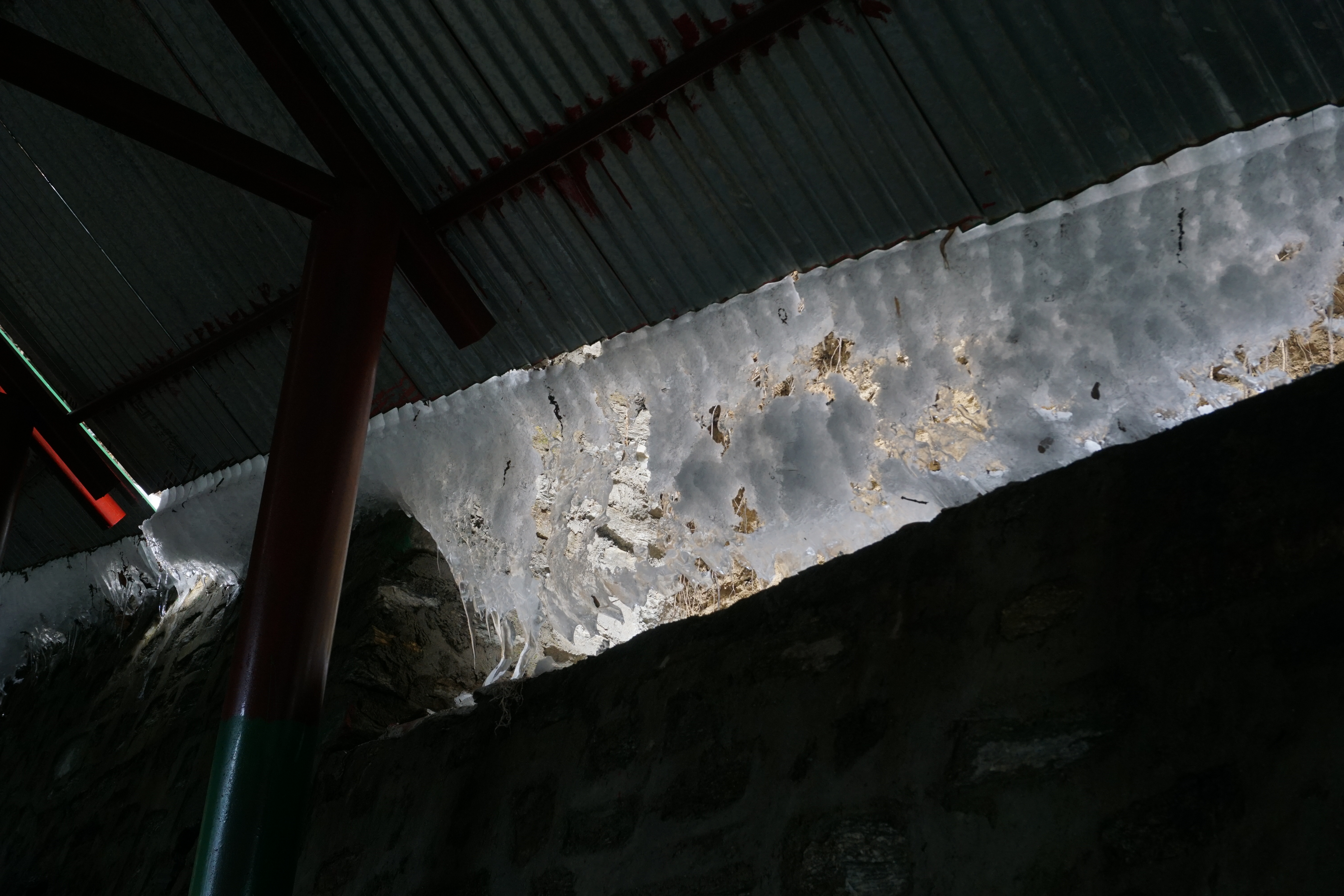 Accumulated ice sliding off like a fluid through the corrugated channels of the roof.