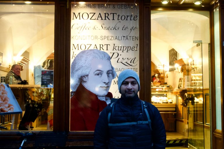 Partho posing in front of a bakery carrying Mozart&rsquo;s name. I tried the Austrian Leberkässemmel sandwich here.