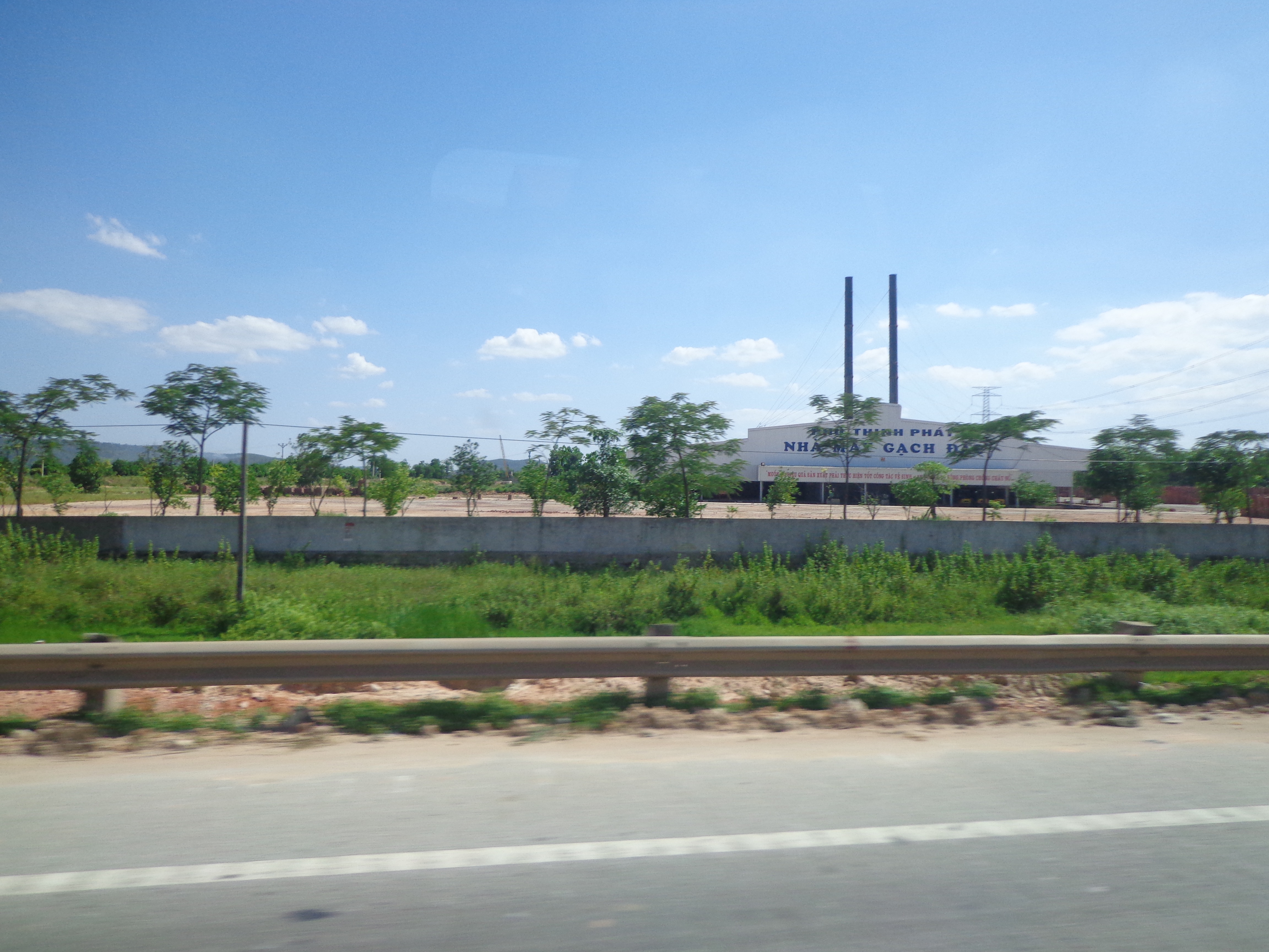 A village with a factory. The factory is surrounded by rice fields.