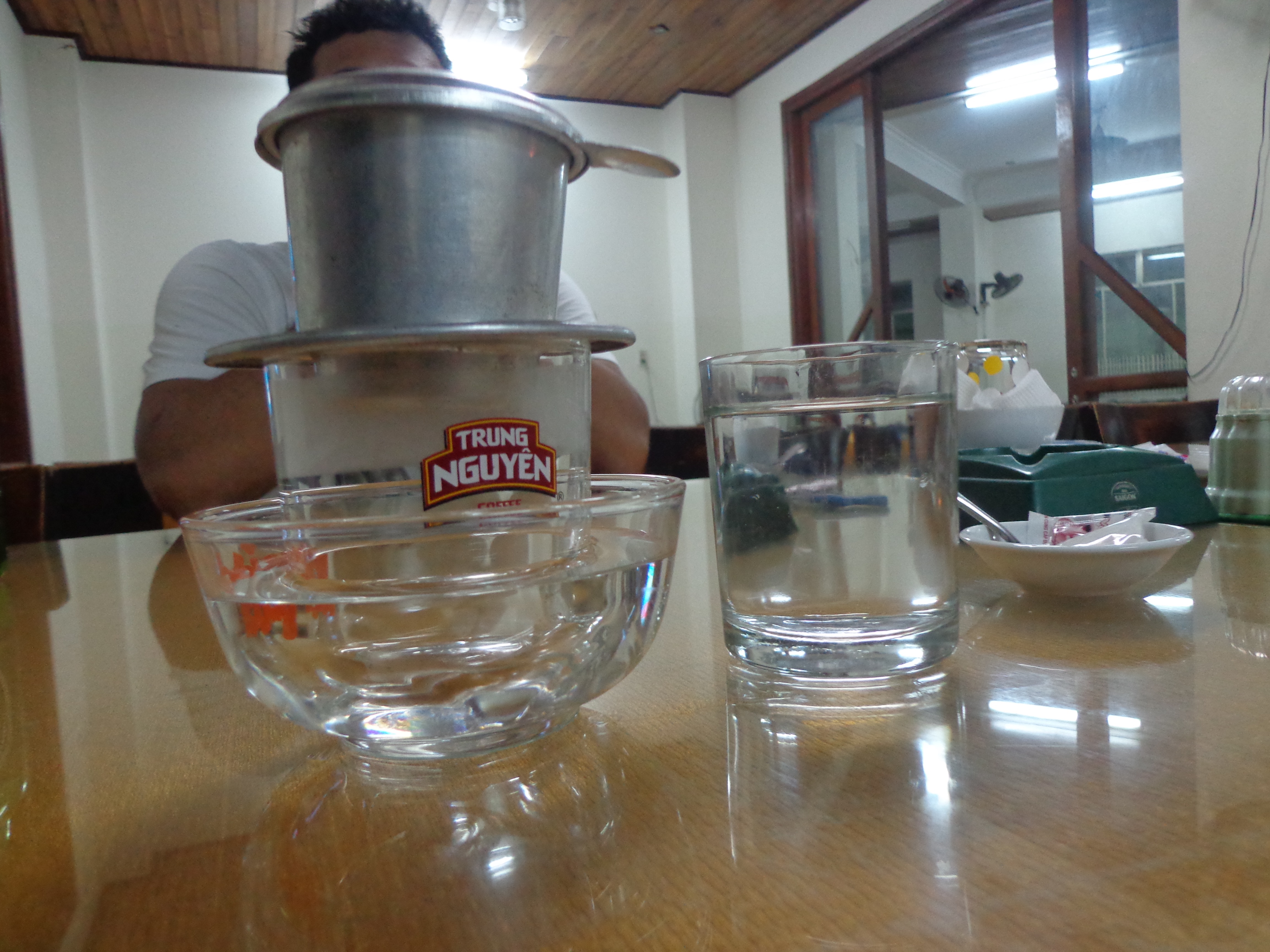 This is how a traditional Vietnamese coffee is brewed. The perforated aluminium container has roasted coffee powder. Hot water is poured inside and is allowed to trickle into the the glass to make the concoction.