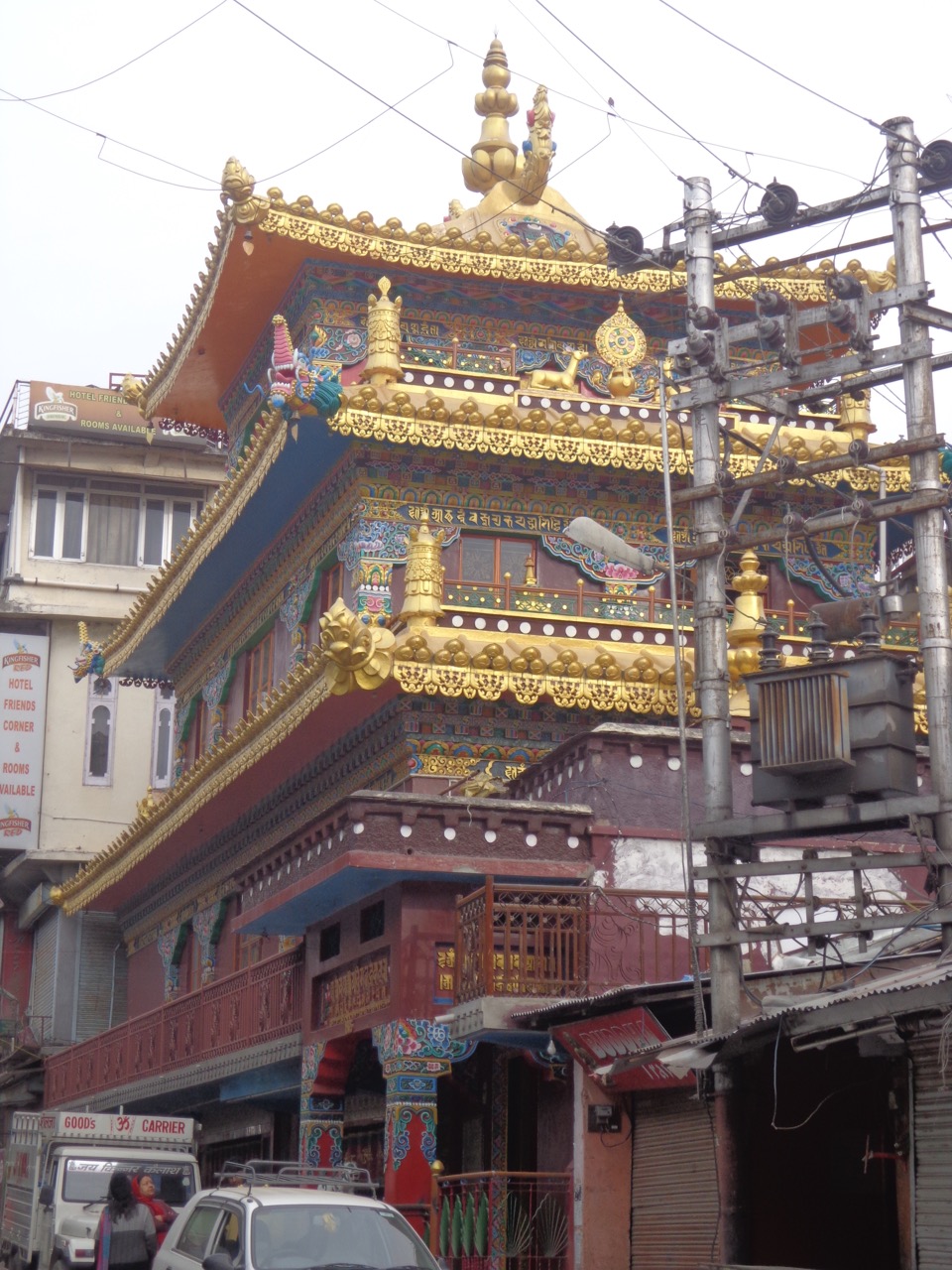 Kalachakra Temple sandwiched between modern eateries, shops and an electrical transformer.